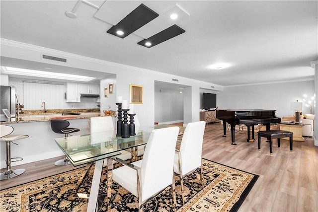 dining area with light hardwood / wood-style floors, sink, and crown molding