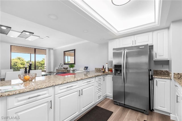 kitchen featuring kitchen peninsula, ornamental molding, white cabinets, stainless steel fridge with ice dispenser, and light hardwood / wood-style floors