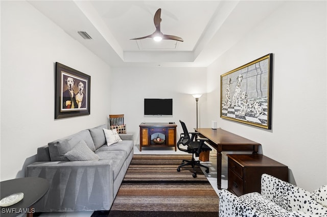 office featuring visible vents, a raised ceiling, and a ceiling fan