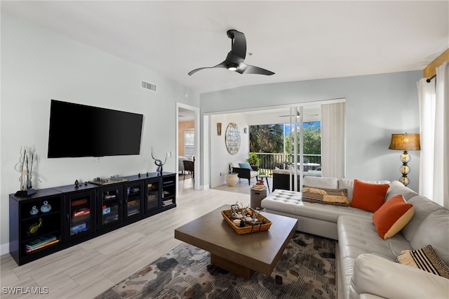 living area featuring a ceiling fan, vaulted ceiling, visible vents, and light wood-style floors