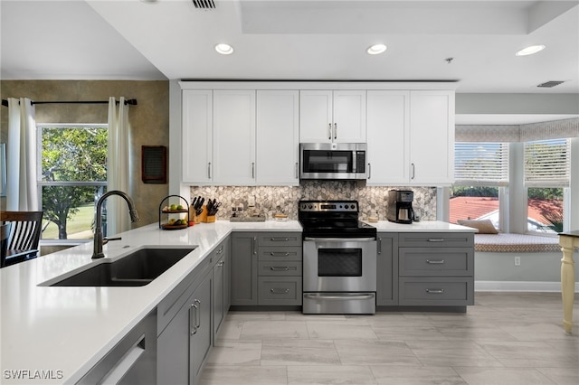 kitchen featuring white cabinets, gray cabinets, stainless steel appliances, and light countertops