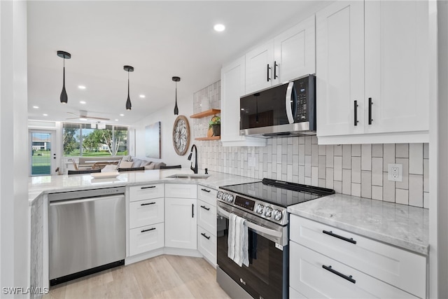 kitchen featuring stainless steel appliances, pendant lighting, decorative backsplash, sink, and white cabinetry