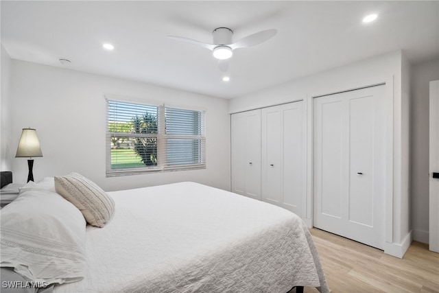 bedroom with multiple closets, ceiling fan, and light hardwood / wood-style flooring