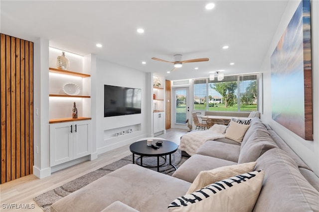 living room featuring light wood-type flooring, ceiling fan, and built in features