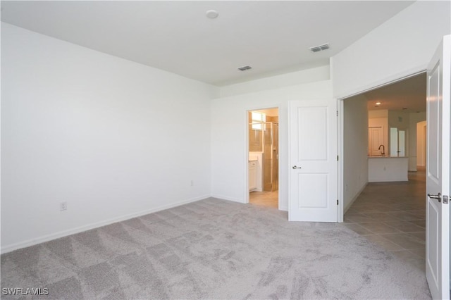 unfurnished bedroom with light carpet and connected bathroom