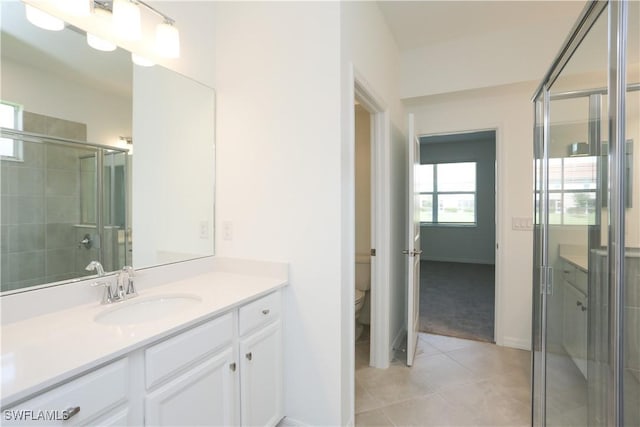 bathroom featuring toilet, a shower with door, vanity, and tile patterned floors