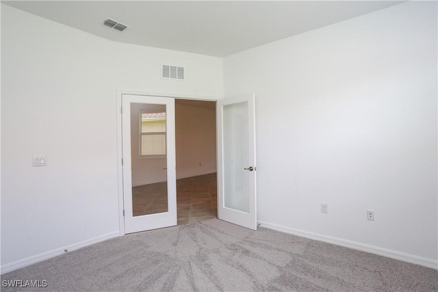 carpeted empty room featuring french doors