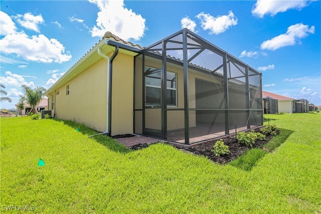 view of side of property featuring a yard and glass enclosure