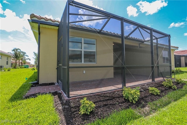 view of side of property featuring a lawn, a lanai, and a patio