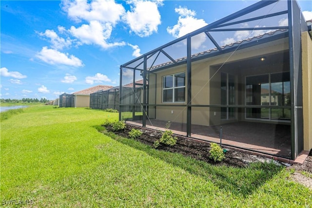 view of yard with a lanai, a patio area, and a water view