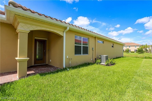 rear view of house featuring cooling unit and a lawn