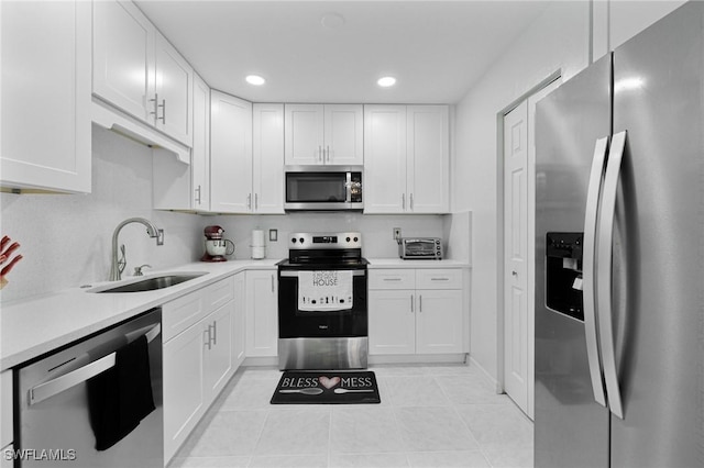 kitchen featuring light tile patterned floors, appliances with stainless steel finishes, white cabinets, and sink