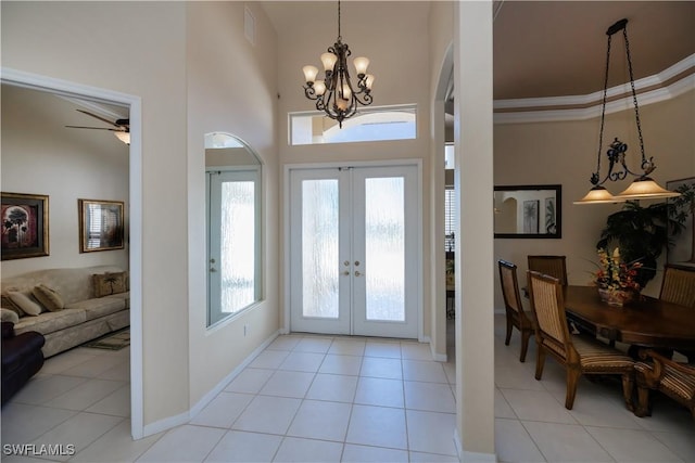 foyer featuring french doors, ornamental molding, a chandelier, and light tile patterned floors