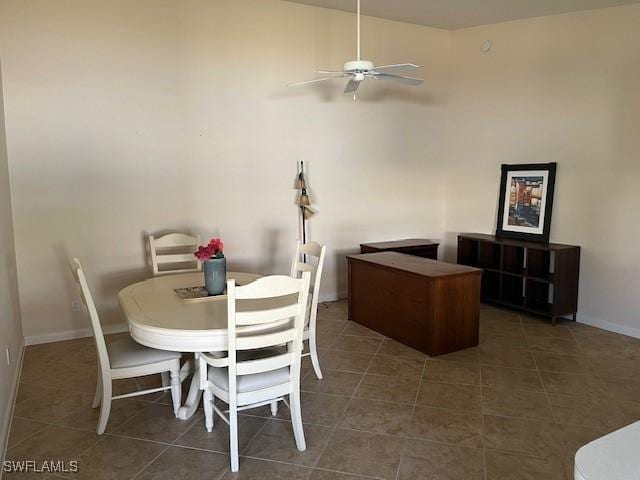 dining space featuring ceiling fan and dark tile patterned flooring