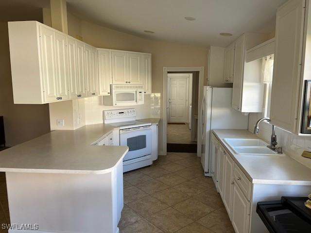 kitchen featuring light tile patterned floors, white cabinetry, kitchen peninsula, white appliances, and sink