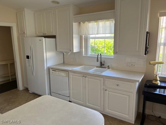 kitchen with plenty of natural light, sink, white appliances, and white cabinetry