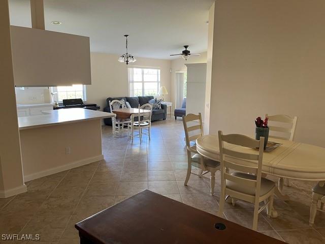 dining area featuring ceiling fan with notable chandelier and light tile patterned flooring