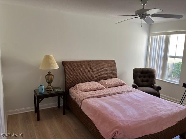 bedroom with ceiling fan, hardwood / wood-style floors, and multiple windows