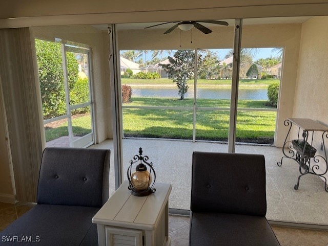 sunroom / solarium featuring ceiling fan and a water view