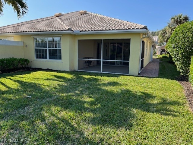 back of property featuring a sunroom and a lawn