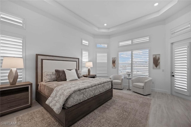 bedroom featuring light hardwood / wood-style floors and a tray ceiling