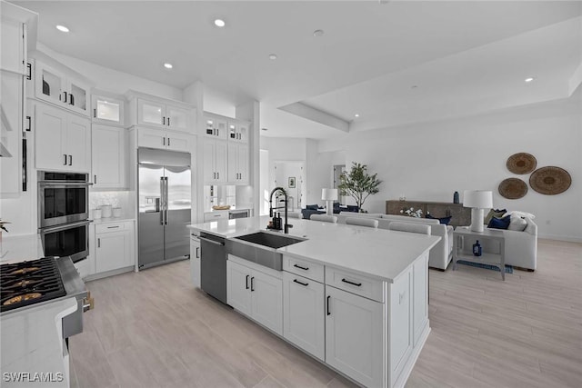 kitchen with sink, white cabinetry, a kitchen island with sink, and appliances with stainless steel finishes