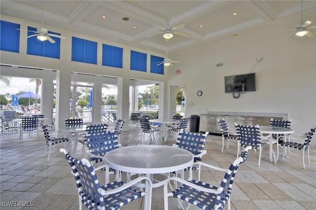 dining room featuring coffered ceiling, a towering ceiling, a healthy amount of sunlight, and beamed ceiling