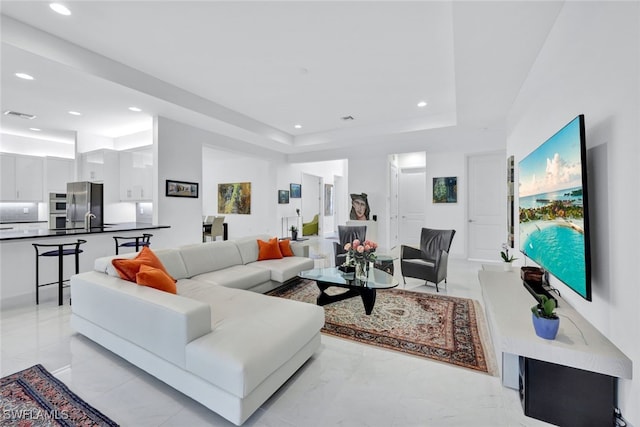 living room featuring a raised ceiling and sink