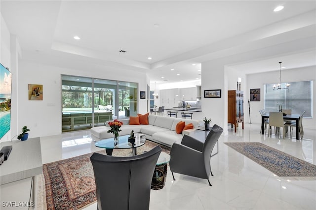 living room featuring a raised ceiling and a notable chandelier