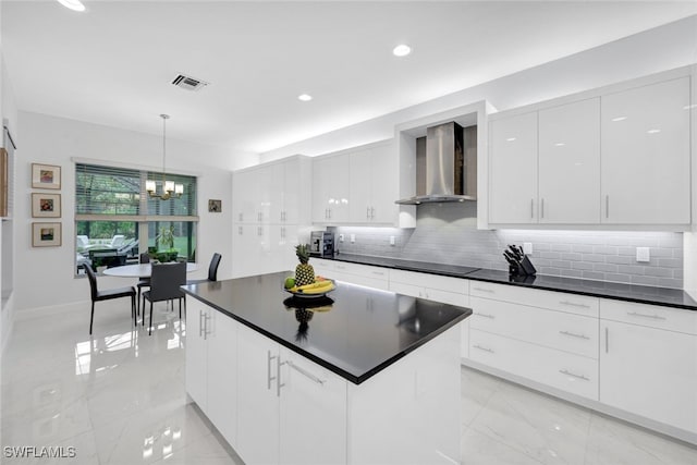 kitchen with pendant lighting, decorative backsplash, cooktop, white cabinetry, and wall chimney exhaust hood