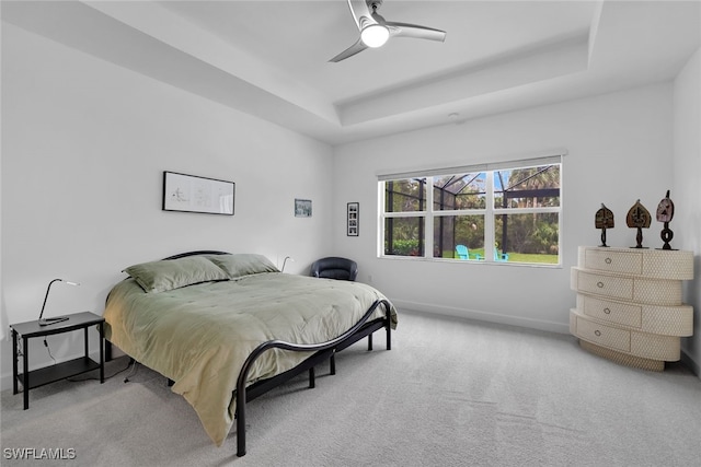 bedroom featuring ceiling fan, light colored carpet, and a tray ceiling