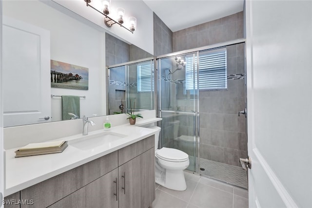 bathroom featuring toilet, tile patterned floors, vanity, and a shower with shower door