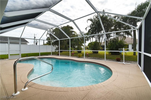 view of pool with glass enclosure, a lawn, and a patio