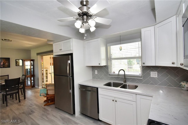 kitchen with tasteful backsplash, white cabinets, appliances with stainless steel finishes, and sink