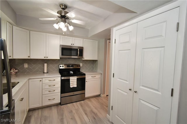 kitchen featuring light wood-type flooring, stainless steel appliances, white cabinets, and tasteful backsplash