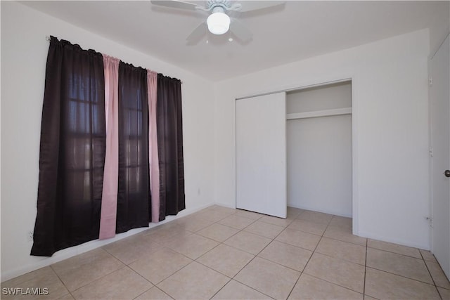 unfurnished bedroom with ceiling fan, light tile patterned floors, and a closet