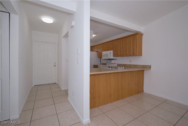 kitchen with light brown cabinetry, light tile patterned floors, and white appliances