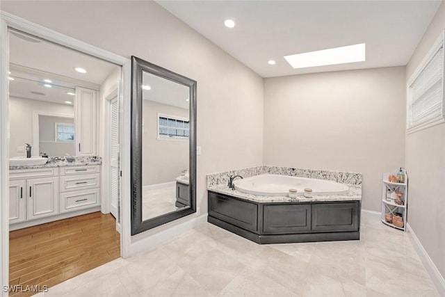 bathroom with a bathing tub, a skylight, and vanity