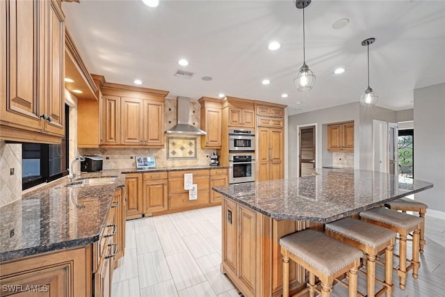 kitchen featuring a kitchen island, backsplash, hanging light fixtures, and wall chimney range hood