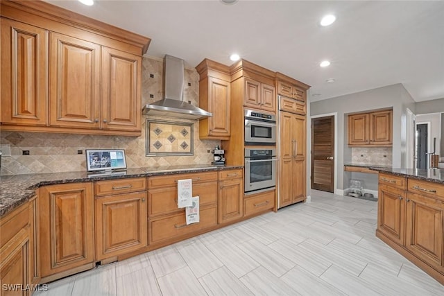 kitchen featuring dark stone countertops, backsplash, and wall chimney range hood