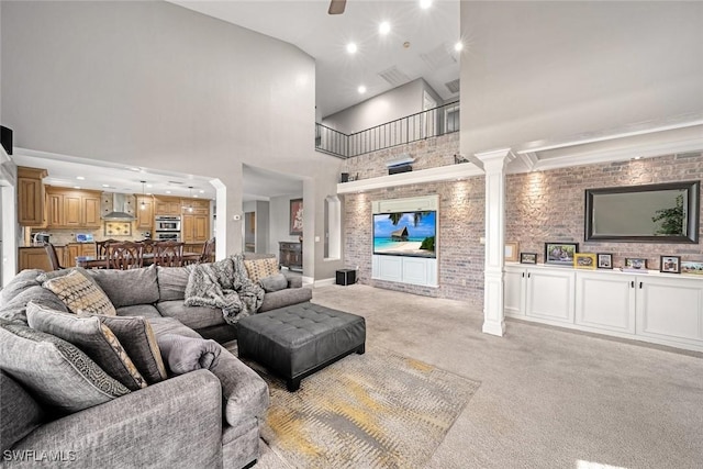 living room featuring ceiling fan, light colored carpet, a towering ceiling, and decorative columns