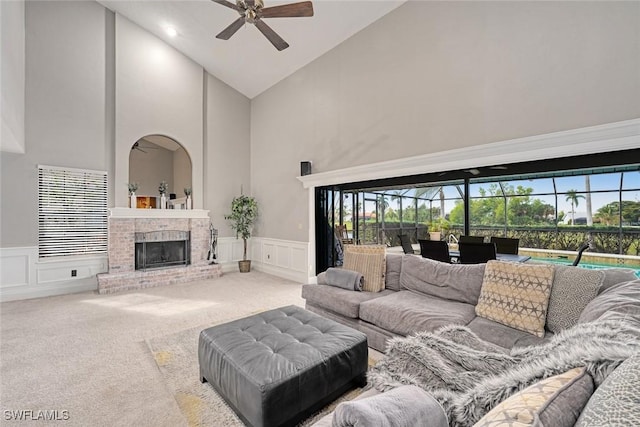 living room featuring high vaulted ceiling, carpet floors, ceiling fan, and a fireplace