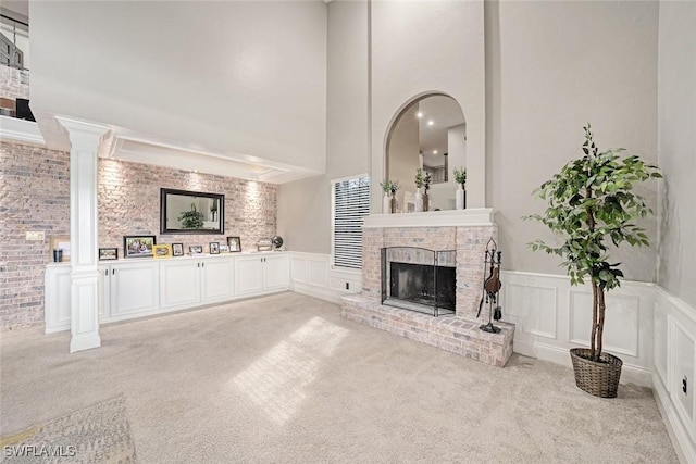 unfurnished living room with light carpet, ornate columns, and a fireplace