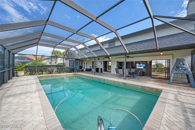 view of pool featuring glass enclosure, ceiling fan, and a patio