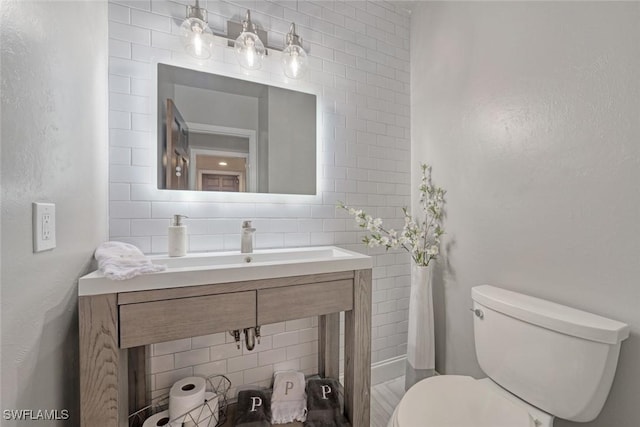 bathroom featuring toilet, backsplash, and sink