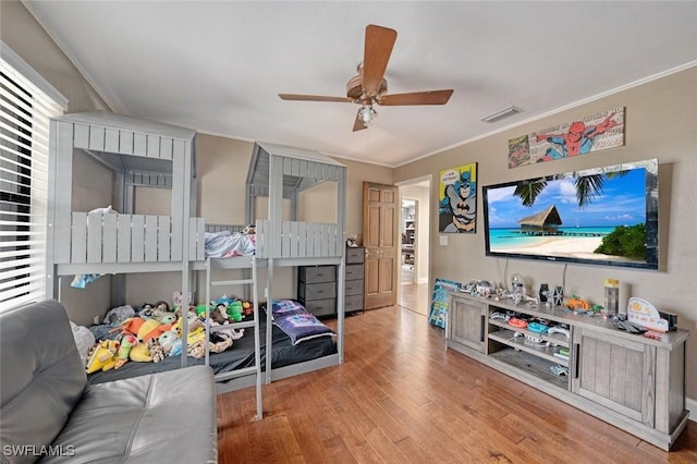 bedroom with ceiling fan, ornamental molding, and light wood-type flooring