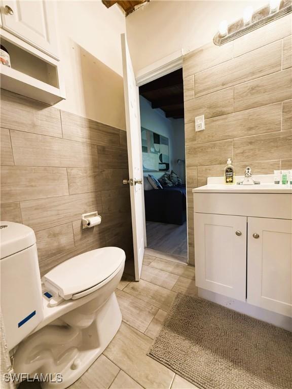 bathroom with vanity, tile walls, and toilet