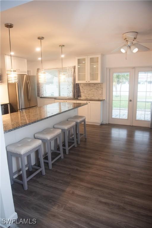 kitchen featuring white cabinets, decorative light fixtures, and stainless steel fridge