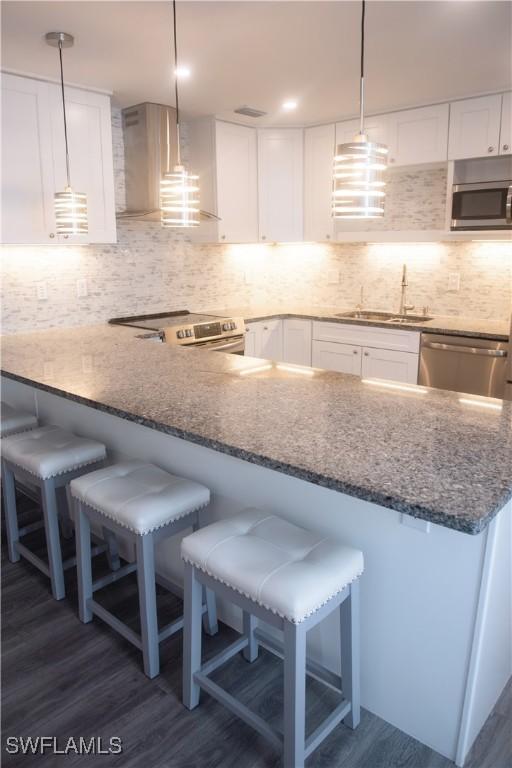 kitchen featuring sink, white cabinets, a kitchen breakfast bar, and hanging light fixtures