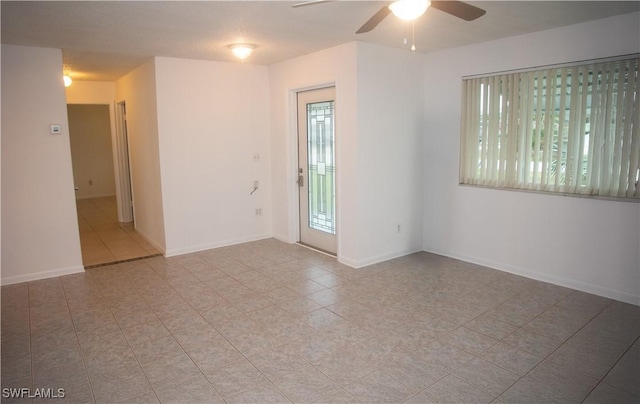 tiled empty room featuring ceiling fan